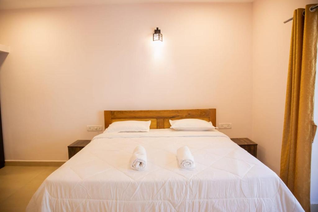 a bedroom with a bed with two white slippers on it at DE 28:11 GUEST HOUSE in Mapusa