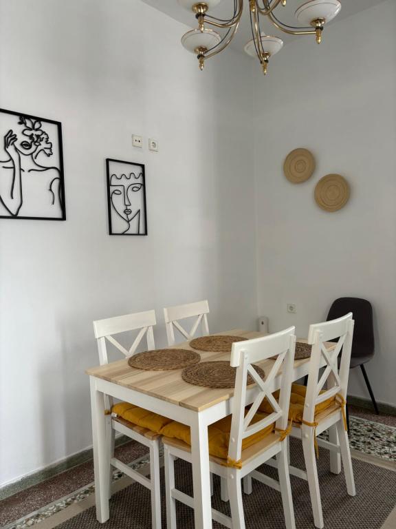 a dining room table with four chairs and a chandelier at Colonia's in Makrakómi