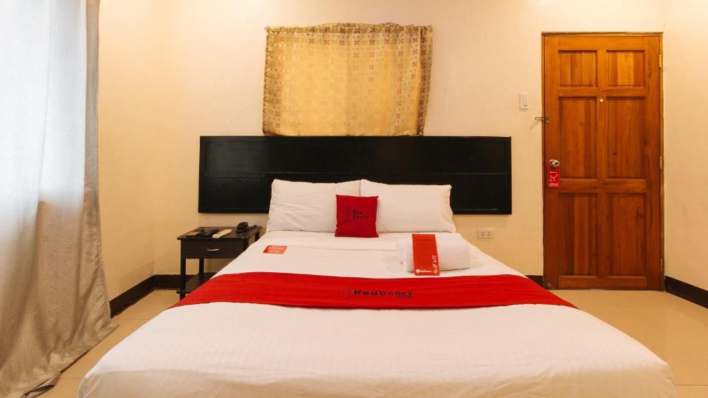 a bedroom with a large white bed with red pillows at RedDoorz at V-Cat Apartelle Sampaloc Manila in Manila