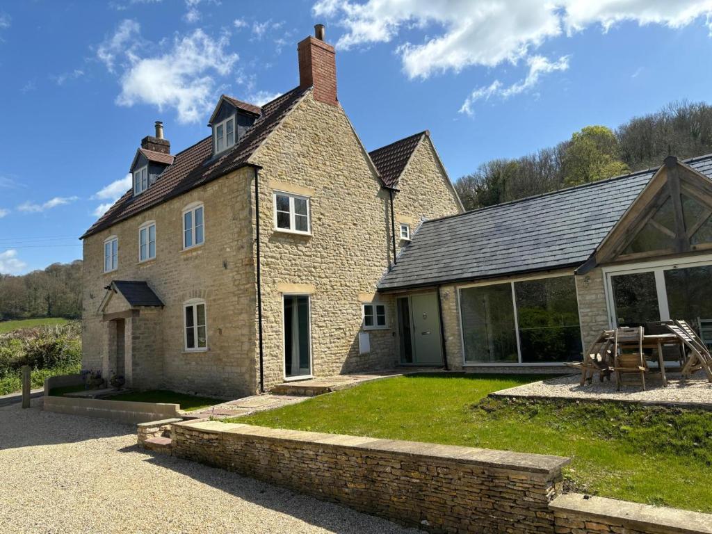 an old brick house with a patio and a yard at Luxury farmhouse in secluded Cotswold valley in Uley