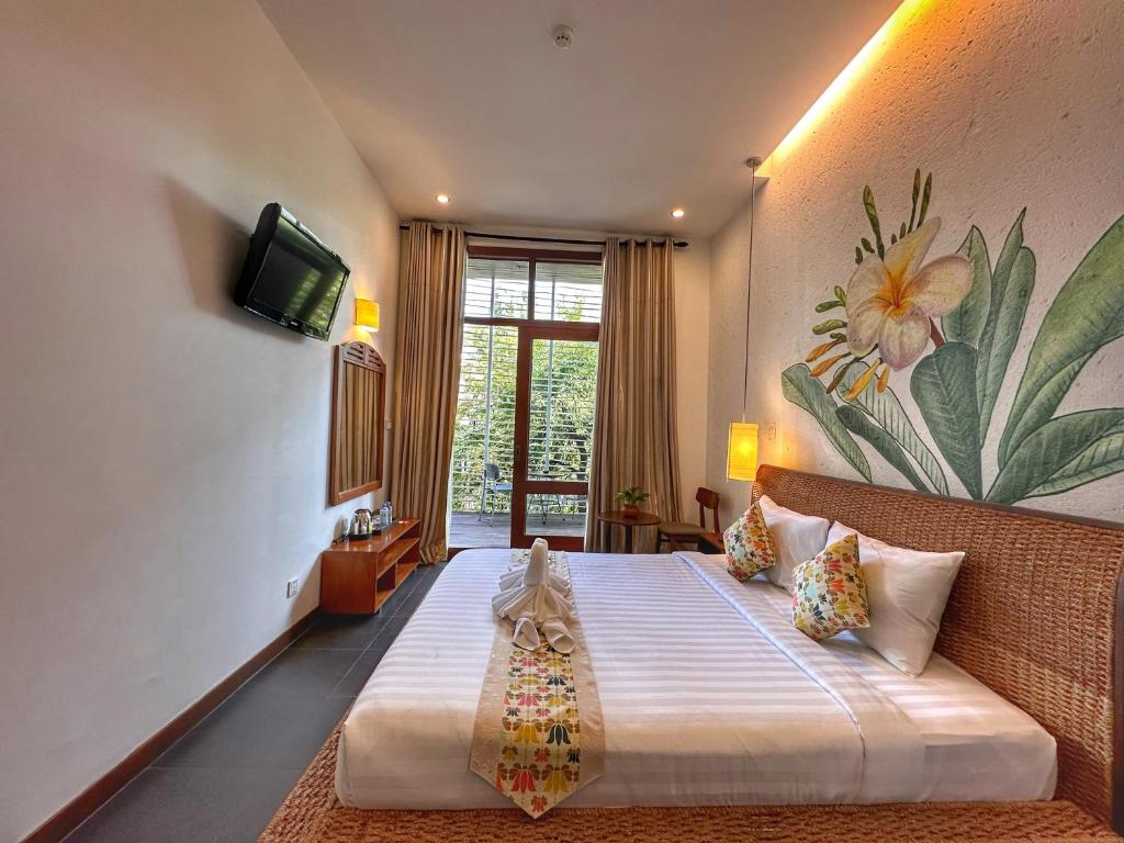 a bedroom with a bed with a television and a flower mural at Monsoon Riverside Hotel in Phnom Penh