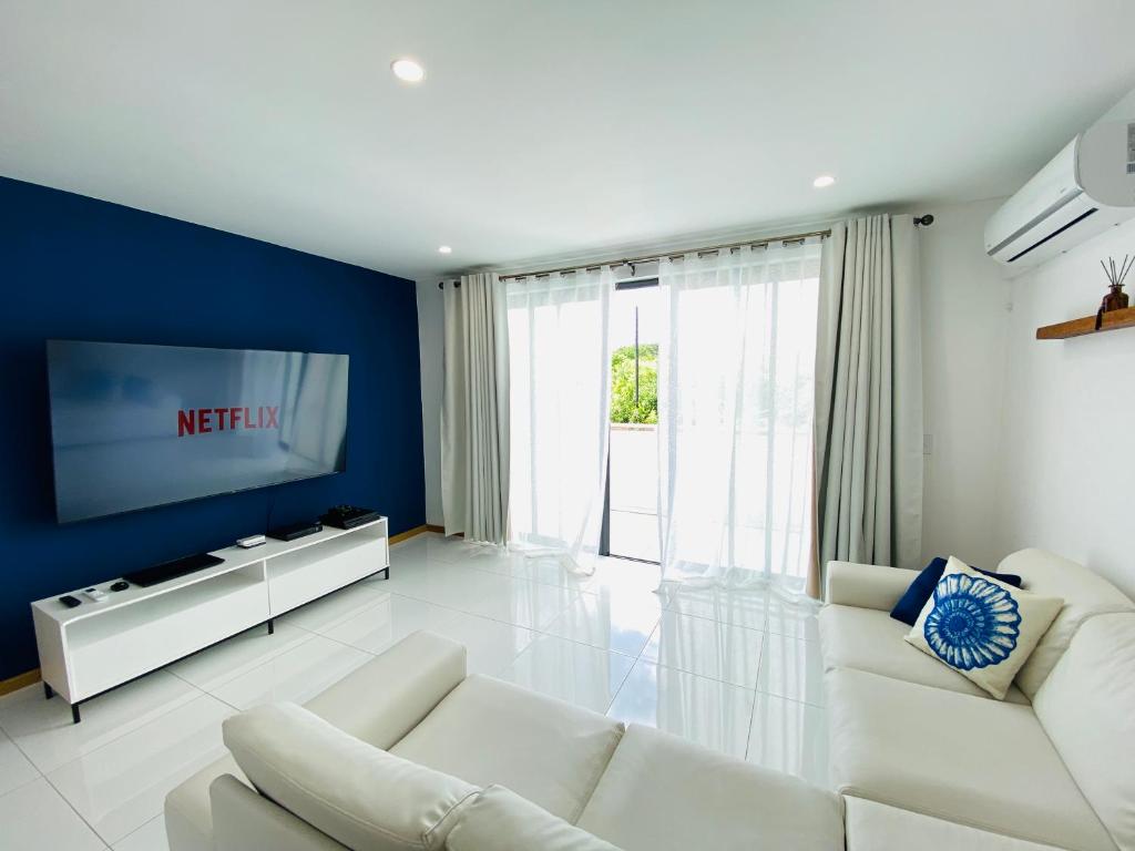 een woonkamer met witte meubels en een blauwe muur bij Villa22 Calodyne in Calodyne