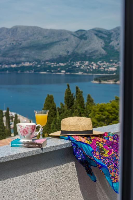 a hat and a book and a cup of orange juice at Sunset view New apartment in Cavtat