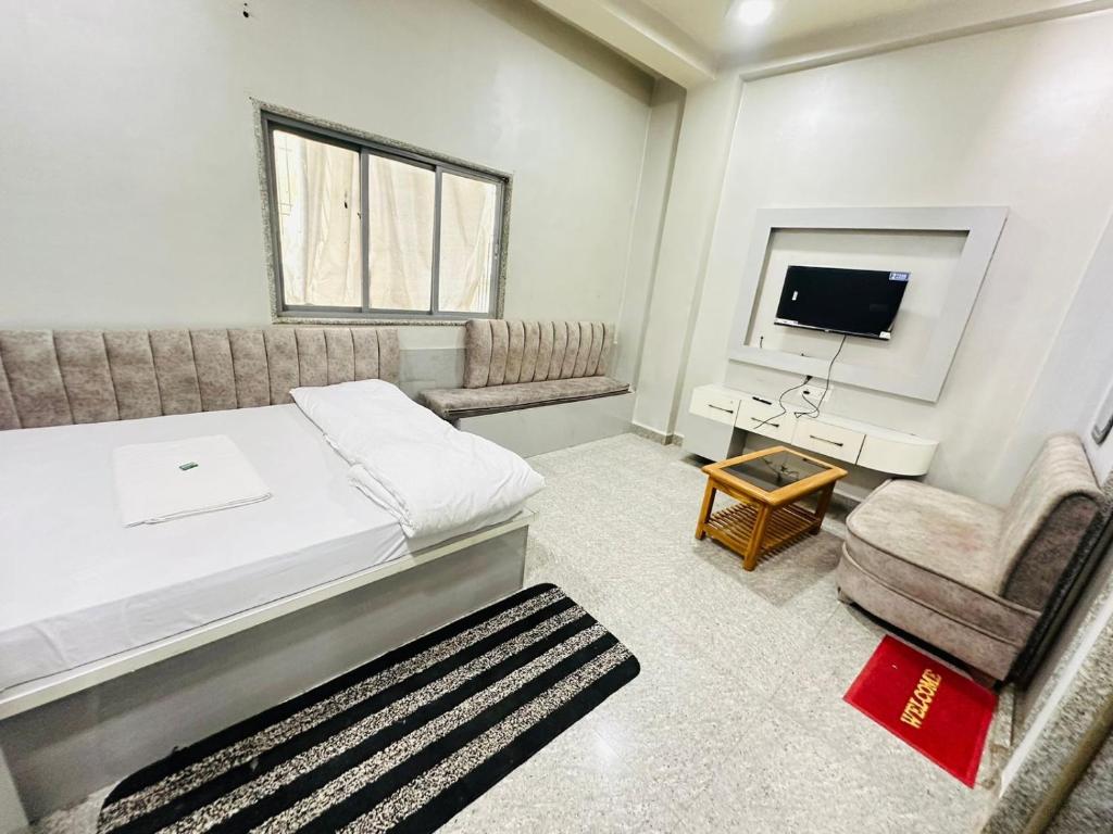 um quarto com uma cama, uma cadeira e uma televisão em HOTEL PRAKASH GUEST HOUSE ! Varanasi ! fully-Air-Conditioned hotel at prime location with off site Parking availability, near Kashi Vishwanath Temple, and Ganga ghat em Varanasi