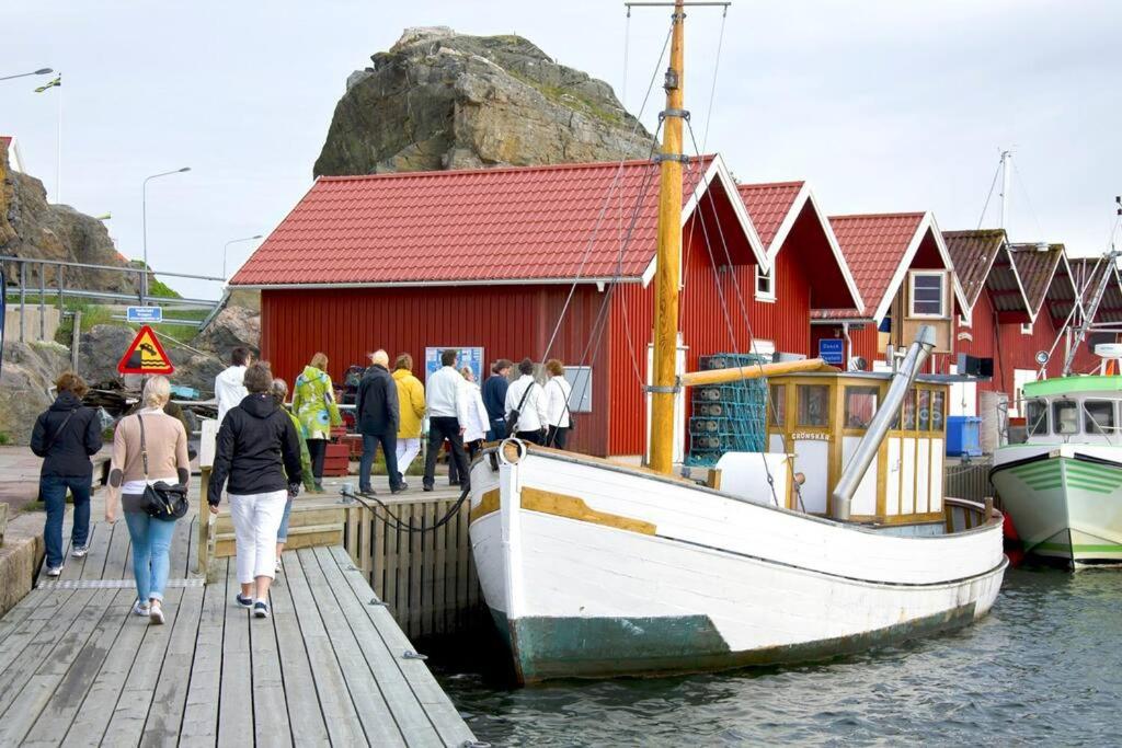 eine Gruppe von Menschen, die auf einem Dock neben einem Boot laufen in der Unterkunft Hus i Skärhamn när till hav och natur! in Utäng