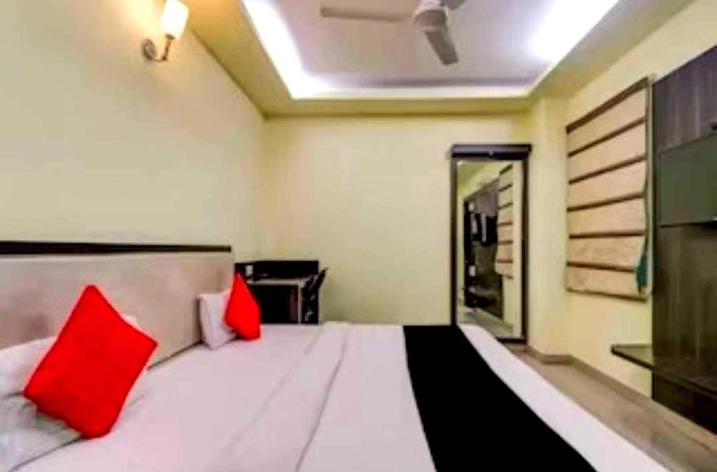 a bedroom with a large white bed with red pillows at Collection O Hotel Kashi Inn in Varanasi