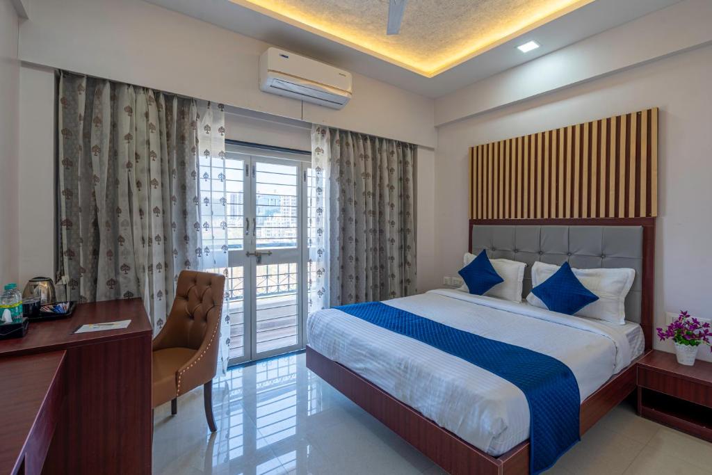 a hotel room with a bed and a desk and a window at StayBird - Divine Suites, Business Hotel, Kharadi in Pune