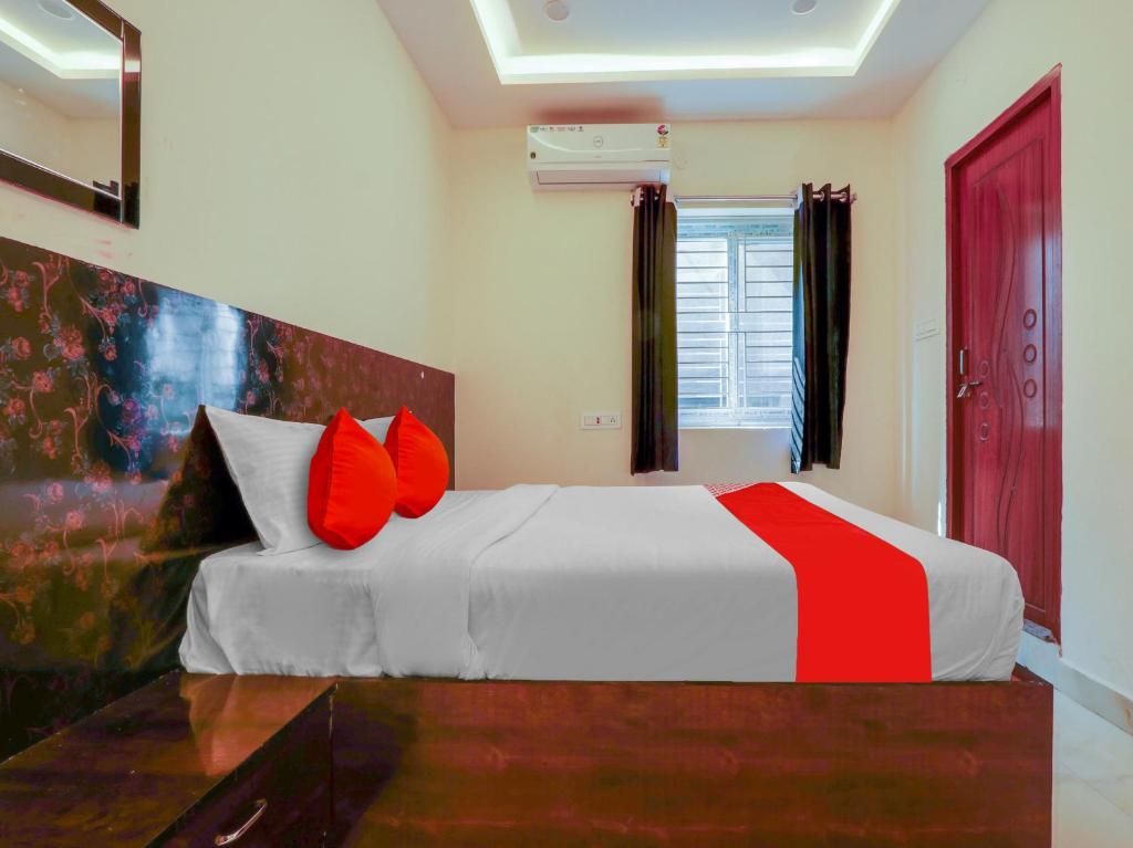 een slaapkamer met een wit bed met rode kussens bij OYO Hotel Apoorva in Shamshabad
