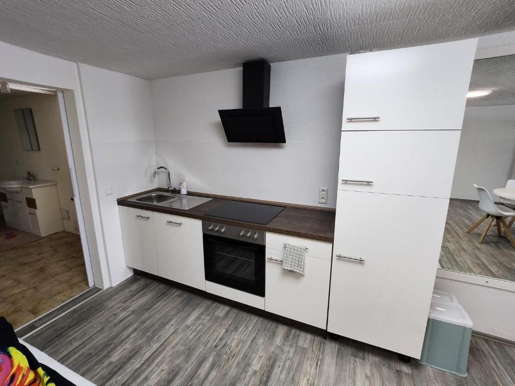 a kitchen with white cabinets and a sink and a stove at Ferienwohnung Marquard's in Immendingen