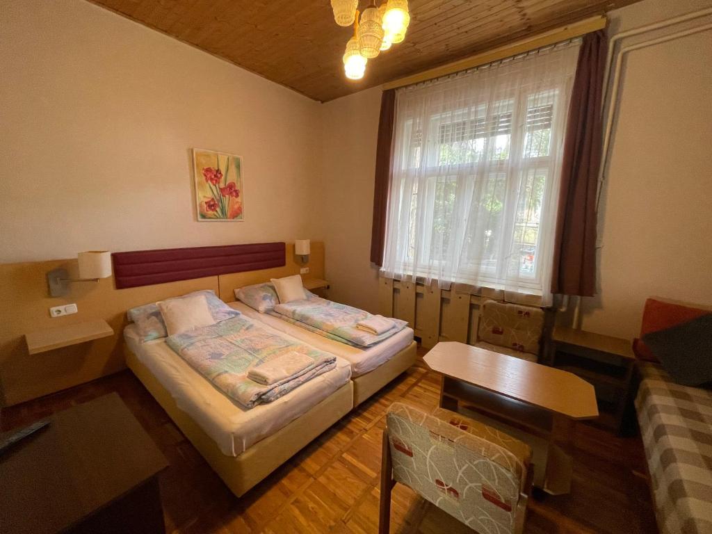 1 dormitorio con 2 camas, mesa y ventana en Alpesi Trimmel Vendégház, en Sopron