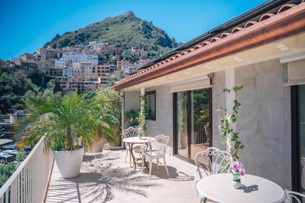 a balcony with tables and chairs and a mountain at Taormina Seaview - Luxury Apartment in Taormina in Taormina