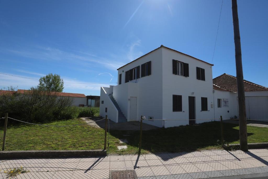 Ein weißes Gebäude mit einem Zaun davor. in der Unterkunft Ria de Aveiro White House in Murtosa
