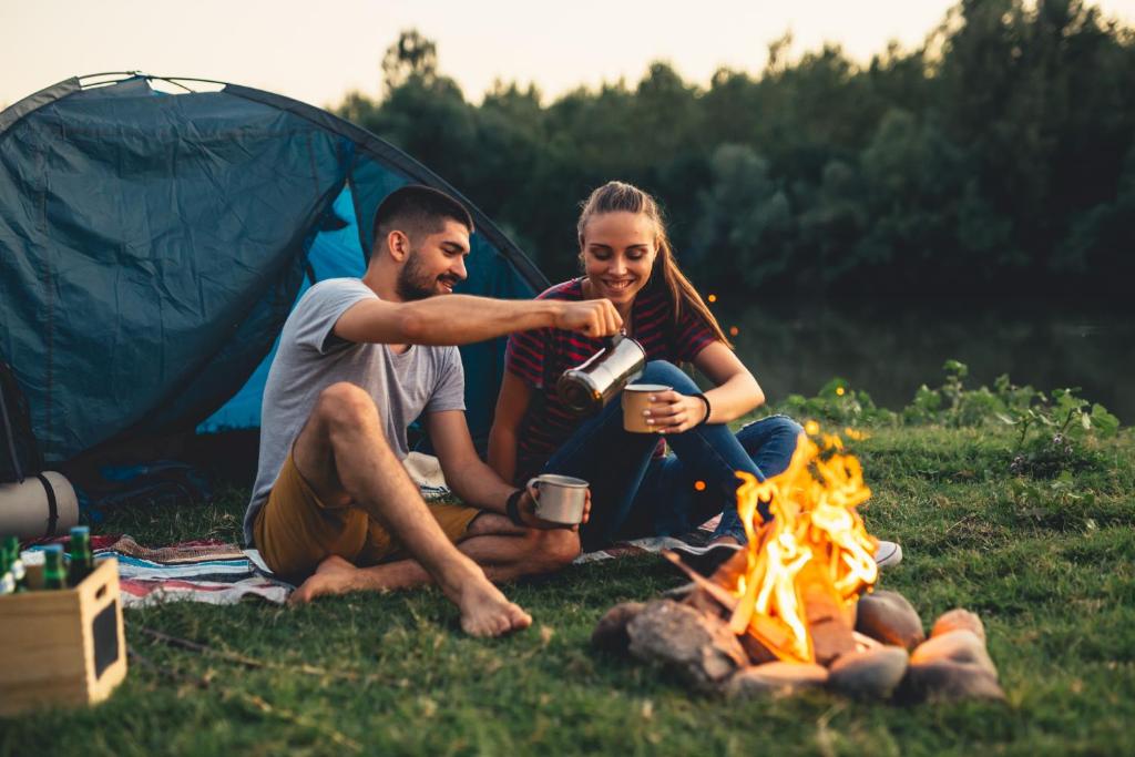 a man and woman sitting next to a campfire at Pole namiotowe Na Haczyku in Nowodwór