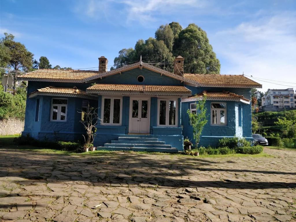 una casa azul sentada en la cima de un campo en FLGHR Crescent Park, en Kodaikanal