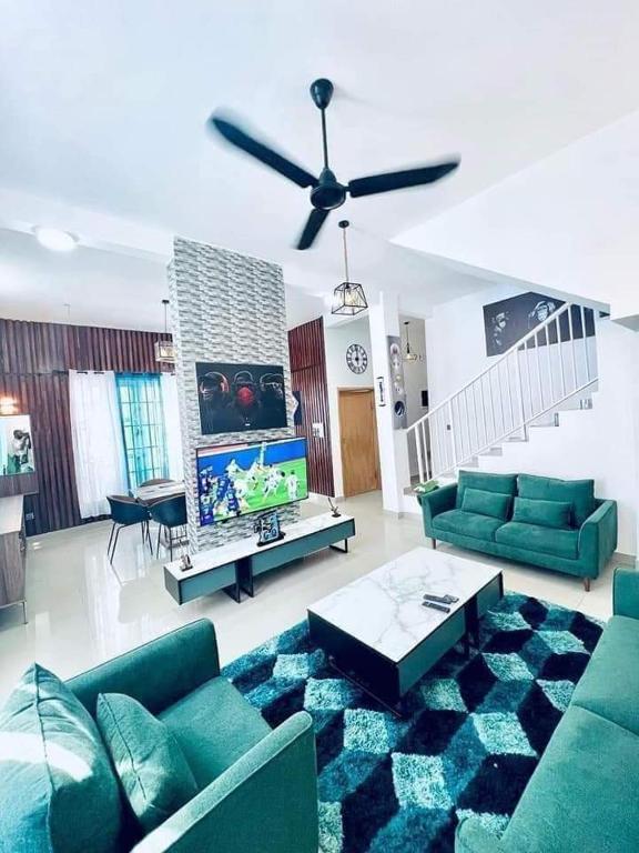 un soggiorno con divani verdi e ventilatore a soffitto di Timba-Pekinoracom a Cotonou