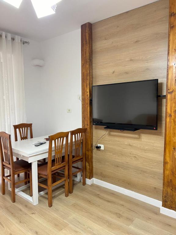 ein Esszimmer mit einem Tisch und Stühlen sowie einem Flachbild-TV in der Unterkunft Glauk Apartment in Berat