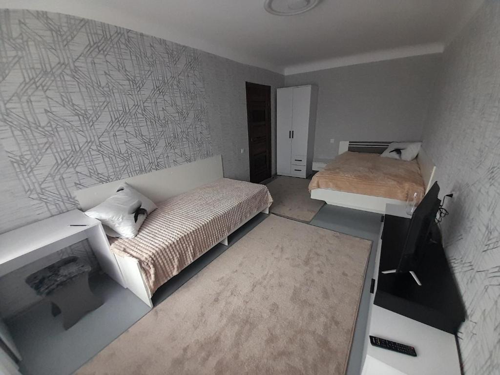 Habitación pequeña con 2 camas y escritorio. en Апартаменти біля Автовокзалу, en Rivne