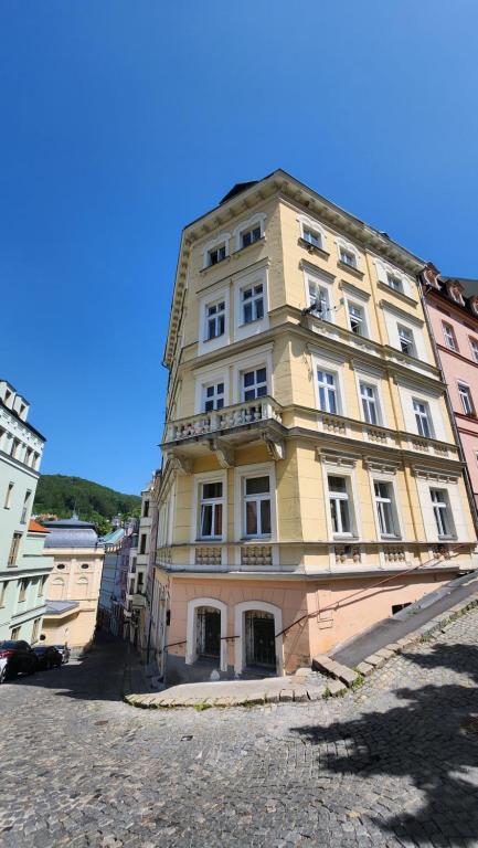 een groot geel gebouw met ramen aan een straat bij Centrum Karlovy Vary Divadelní in Karlsbad