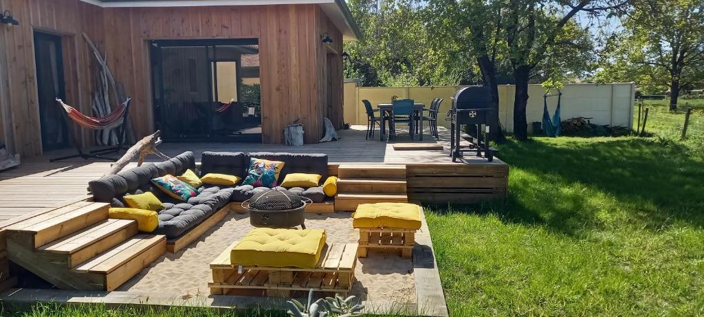 een achtertuin met een bank en stoelen op een terras bij Agréable villa neuve orientée vers la nature et le couché de soleil! in Le Verdon-sur-Mer
