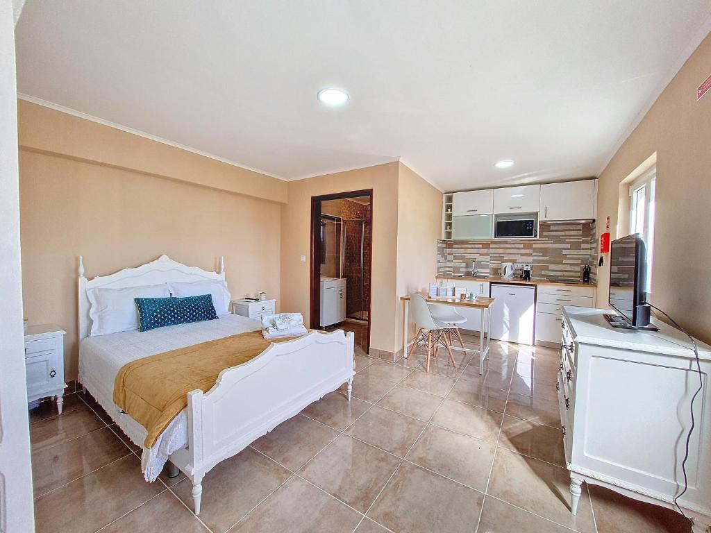 a bedroom with a white bed and a kitchen at Cantinho da Lourdes e Tonito Nº 136193/AL 