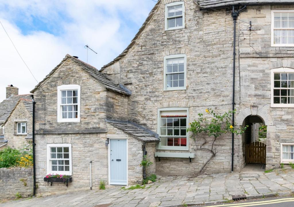 an old stone house with a white door at Wyvern Cottage in Swanage