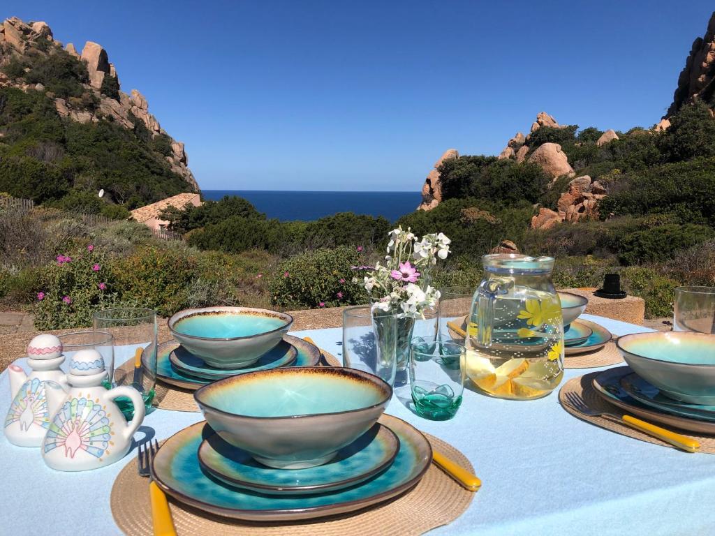 einen Tisch mit Schalen und Tellern mit Meerblick in der Unterkunft Casa Rita in Costa Paradiso