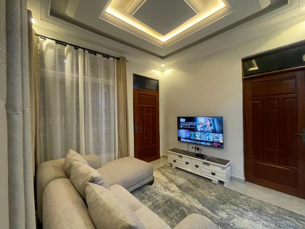Little Sanctuary 1 Bedroom Apartment في دار السلام: غرفة معيشة مع أريكة وتلفزيون بشاشة مسطحة