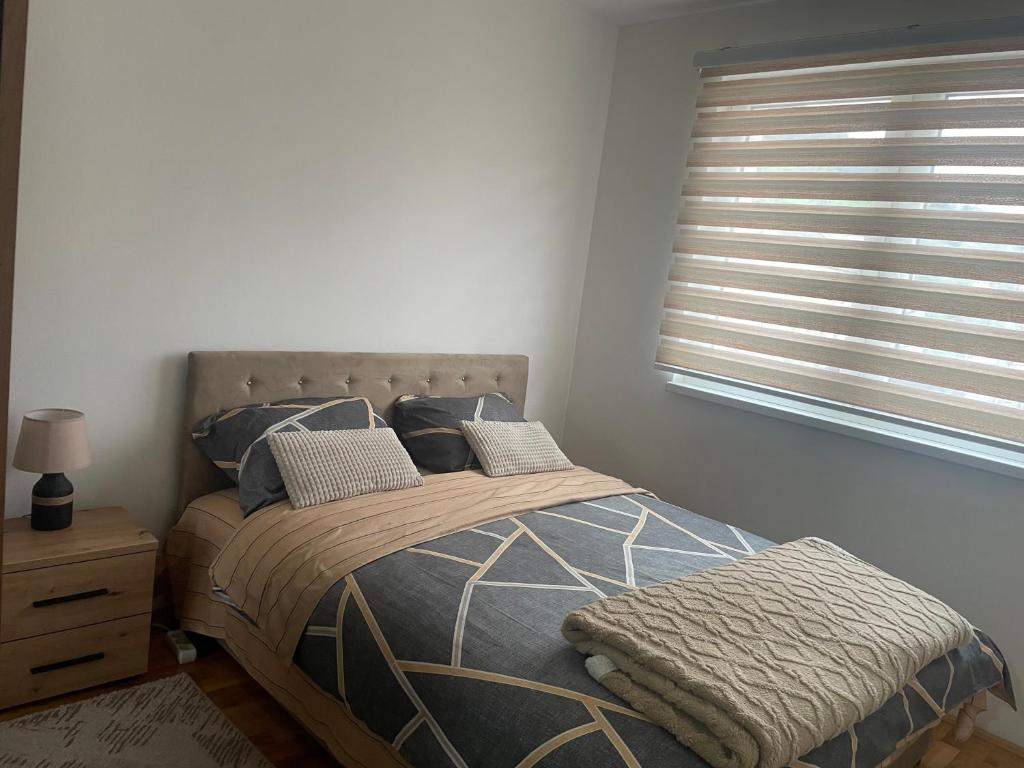 a bedroom with a bed and a window with blinds at Stan na dan Foca in Foča