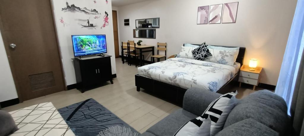- une chambre avec un lit, un canapé et une télévision dans l'établissement Hilanders Condotel Across Terminal 3, à Manille