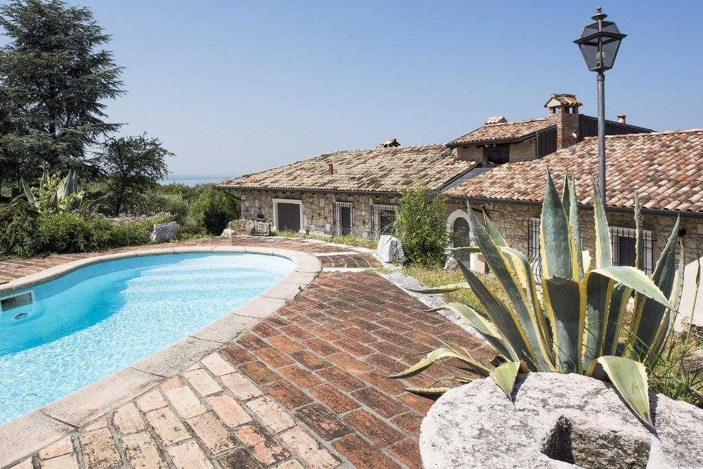 eine Villa mit einem Pool vor einem Haus in der Unterkunft Roel Apartments Lazise in Calmasino