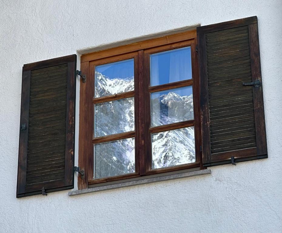 una ventana en un edificio con una montaña cubierta de nieve en Ferienwohnung Seidl Wohnung Kontrabass, en Mittenwald