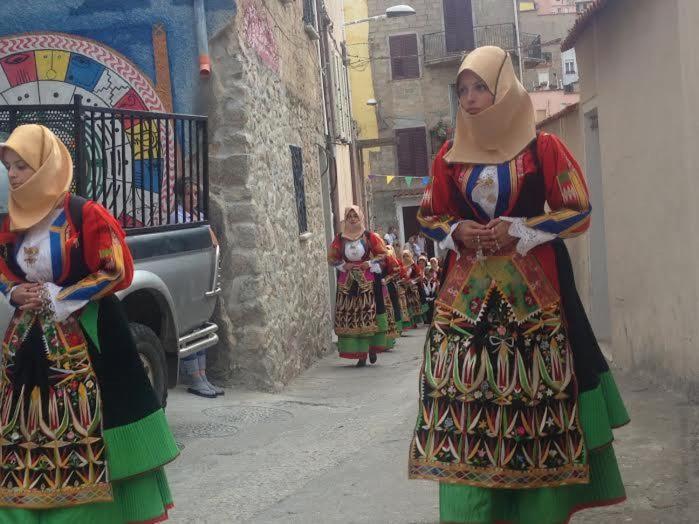 un grupo de mujeres caminando por una calle con en Orgosolo B&B Sardegna, en Orgosolo