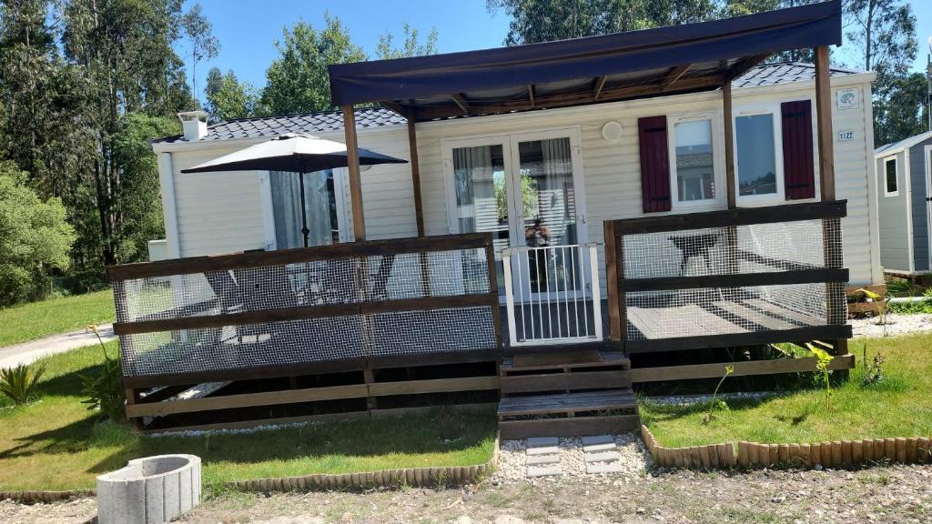 a tiny house with a porch and an umbrella at bungalow jardim bonito 11zz in Pataias