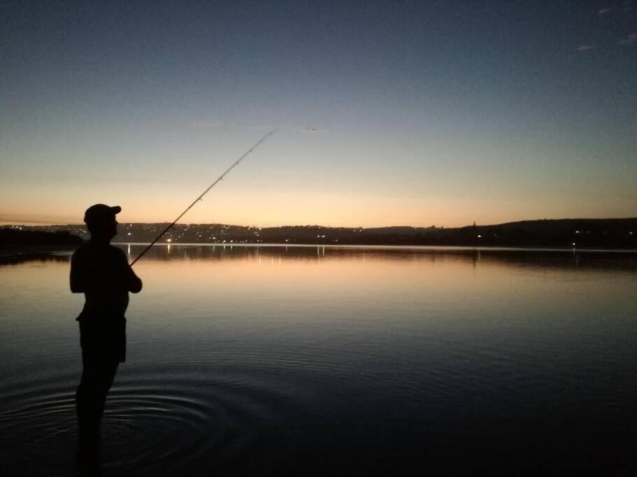 a man standing in the water holding a fishing rod at Keurbooms river, San Marino Complex (Unit 53), Self-catering (Plettenberg Bay) in Keurboomstrand