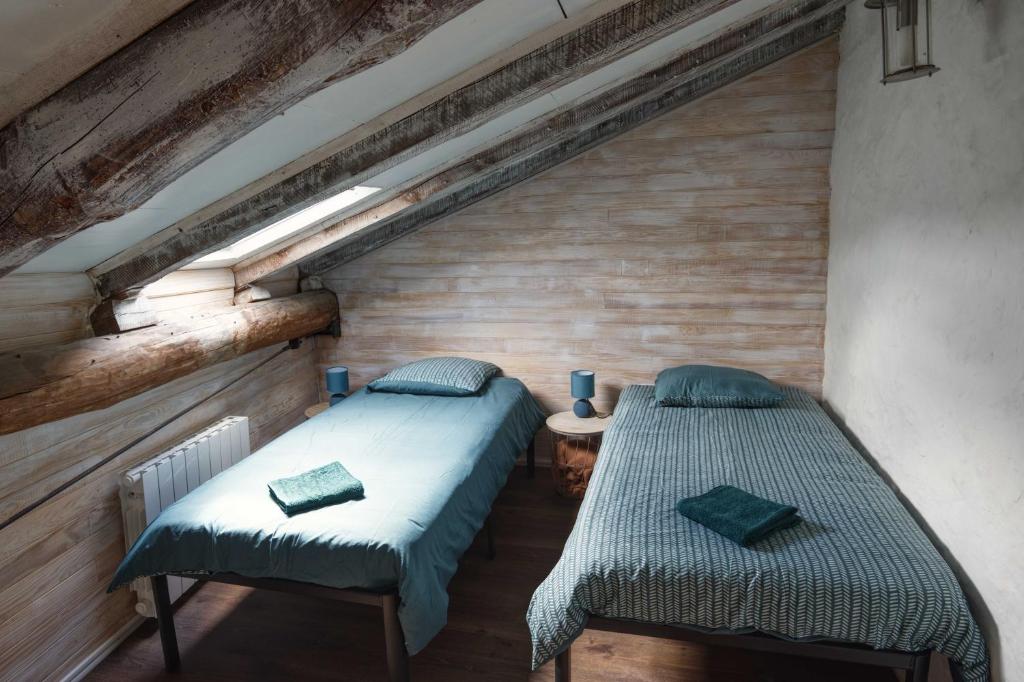 Habitación con 2 camas individuales y paredes de madera. en Le Repose Pieds, en Le Monastier sur Gazeille