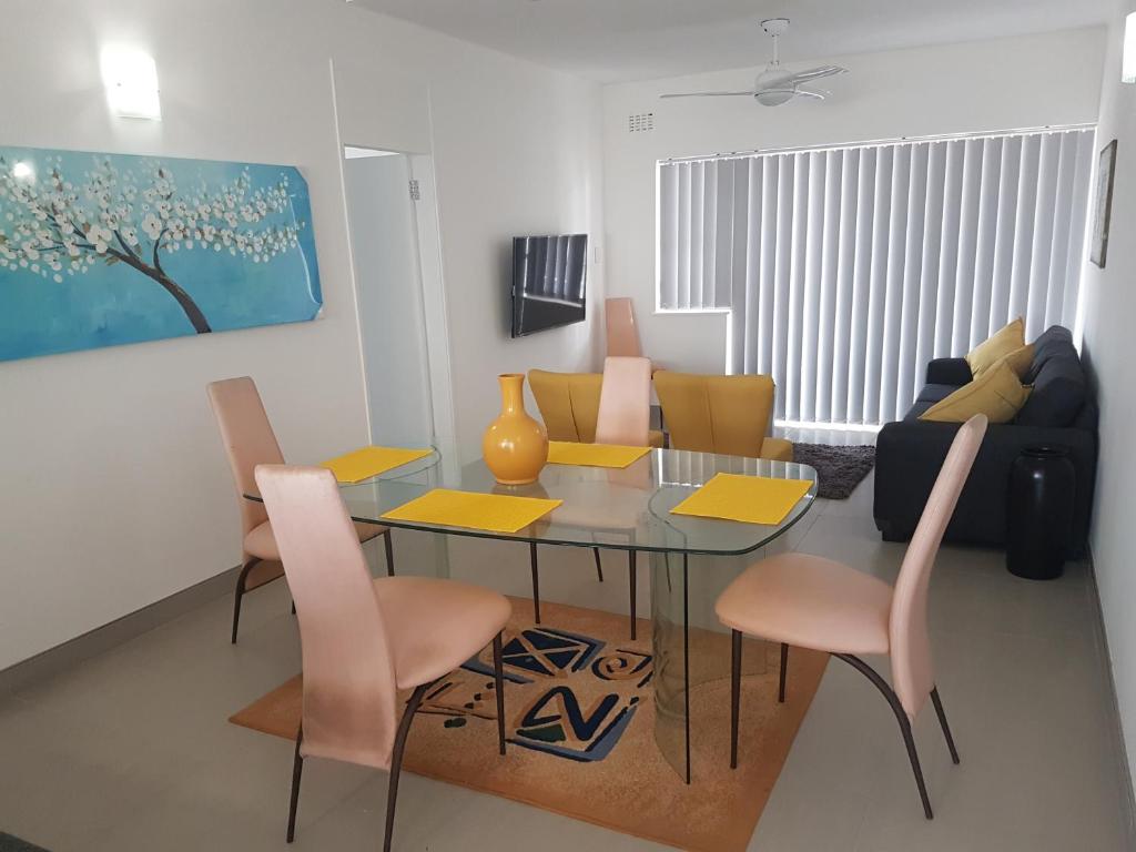 a living room with a dining room table and chairs at 15 BRONZE BEACH UMHLANGA ROCKS DURBAN in Durban