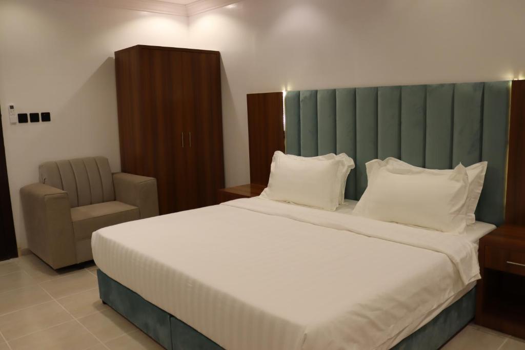 um quarto com uma cama grande e uma cadeira em طيف المكان للشقق الفندقية em Riade