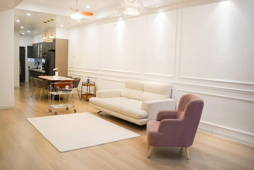 uma sala de estar com um sofá, uma cadeira e uma mesa em French Style Comfy Homestay Alor Setar 现代极简法式温馨民宿 em Alor Setar