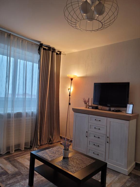 ein Wohnzimmer mit einem TV auf einer Kommode mit einem Tisch in der Unterkunft Giedres Kalnieciu apartments in Kaunas
