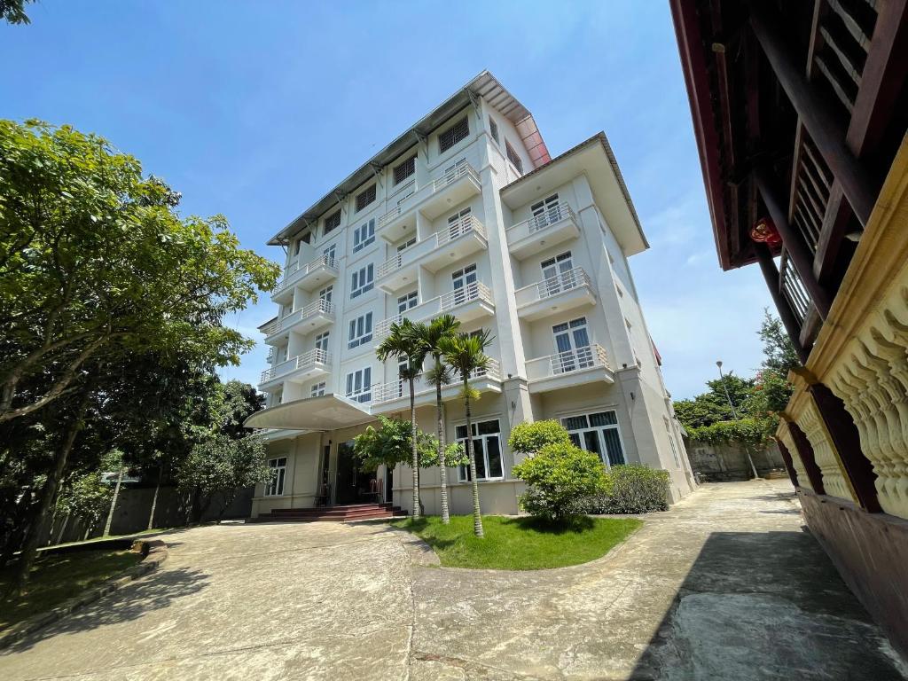 een wit gebouw met een palmboom ervoor bij Thiên Bình Hotel in Hòa Bình