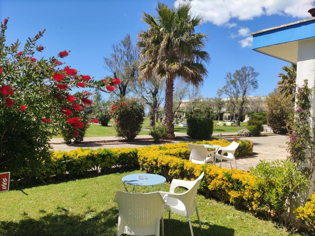 una mesa y sillas en un parque con flores en Riva di Palo Resort en Ladispoli