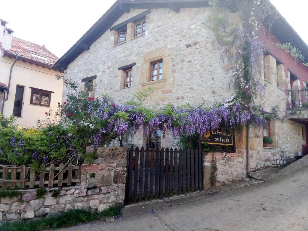 un edificio con flores púrpuras a su lado en La Portiella del Llosu, en Pandiello