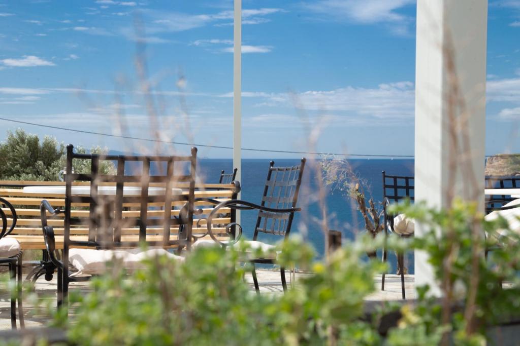 a group of chairs and a table with a view of the ocean at Poseidon Apartments and Villas by the Sea in Sounio