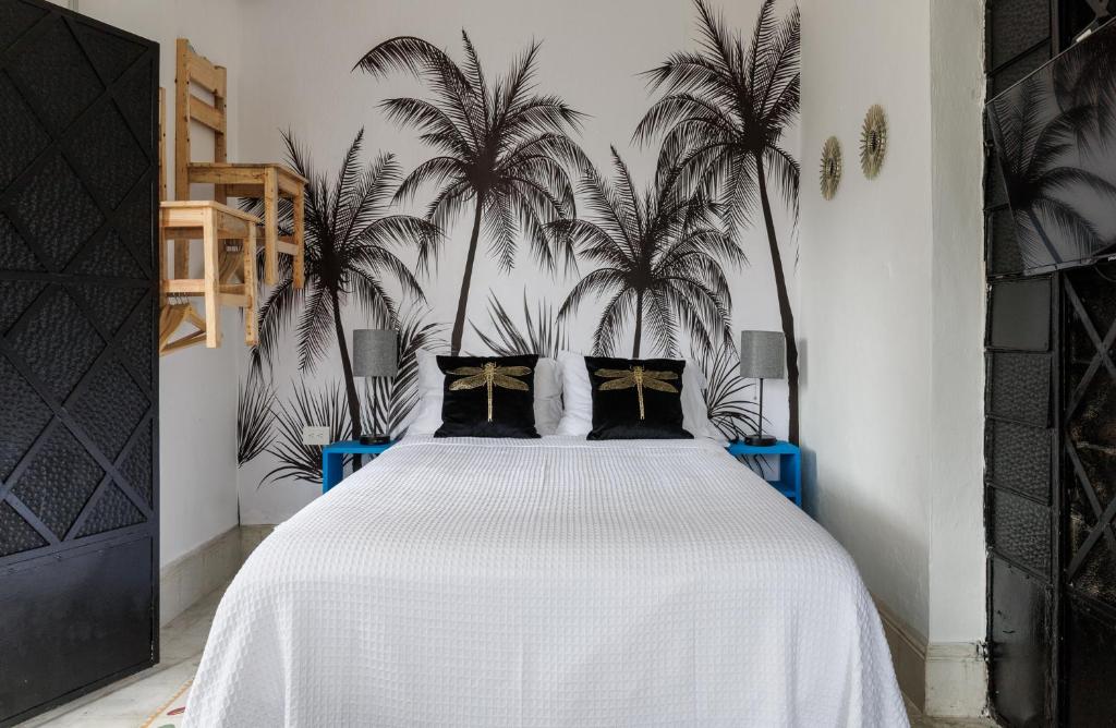 um quarto com uma cama branca com palmeiras em CASA PAXI CENTRO MERIDA ESTUDIO5 em Mérida