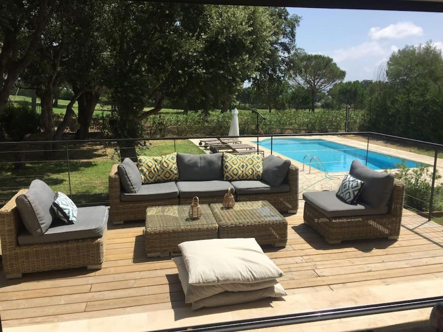 - une terrasse avec des canapés et des chaises à côté de la piscine dans l'établissement Villa Grimaud - au calme sur Golf, et vue mer sur le Golfe de Saint-Tropez, à Grimaud