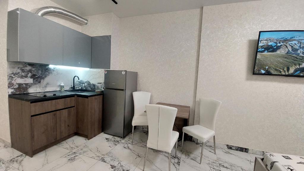 a kitchen with white chairs and a stainless steel refrigerator at Apartments near the sea in Odesa