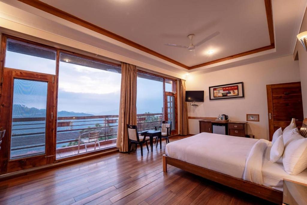 a hotel room with a bed and a large window at Nature View Resort !! A Four Star Lavish & Luxury Resort in Chail