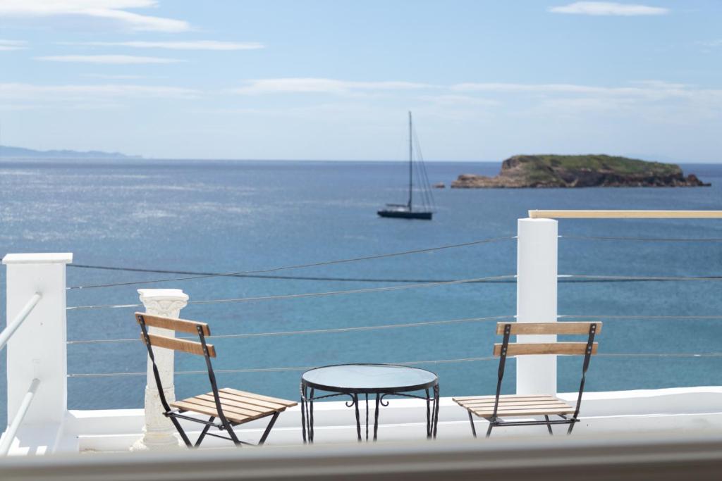 duas cadeiras e uma mesa numa varanda com o oceano em Poseidon Apartments and Villas by the Sea em Sounio