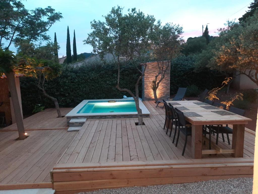une terrasse en bois avec une table et une piscine dans l'établissement Villa en Provence Summer Vibes, à Puget-Ville