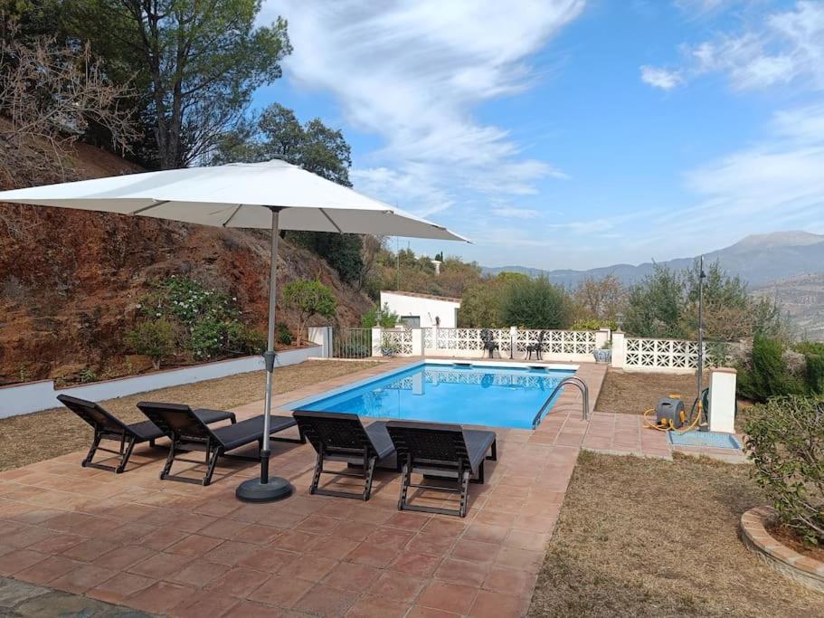- une piscine avec une table, des chaises et un parasol dans l'établissement Casa del Barco with pool and stunning views, à Guaro